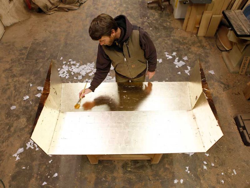 Bay Area furniture designer and CCA alumnus Florian Roeper puts the finishing touches on a gold-leafed surface in his Alameda atelier.