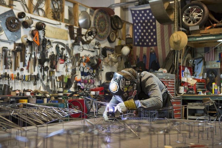Image of artist Shawn HibmaCronan welding in his studio.