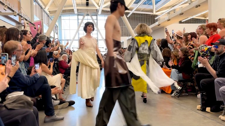 A still from the fashion show with models walking down the runway.