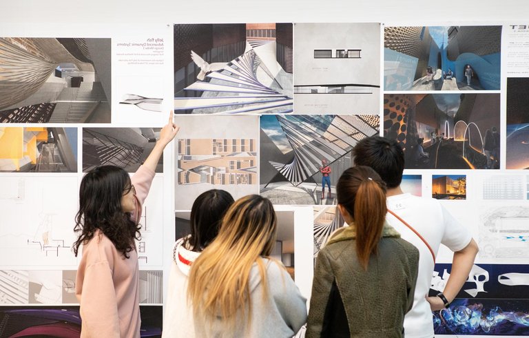 Students viewing critique materials on a wall.