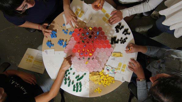 Several people playing the board game The Other 99%.
