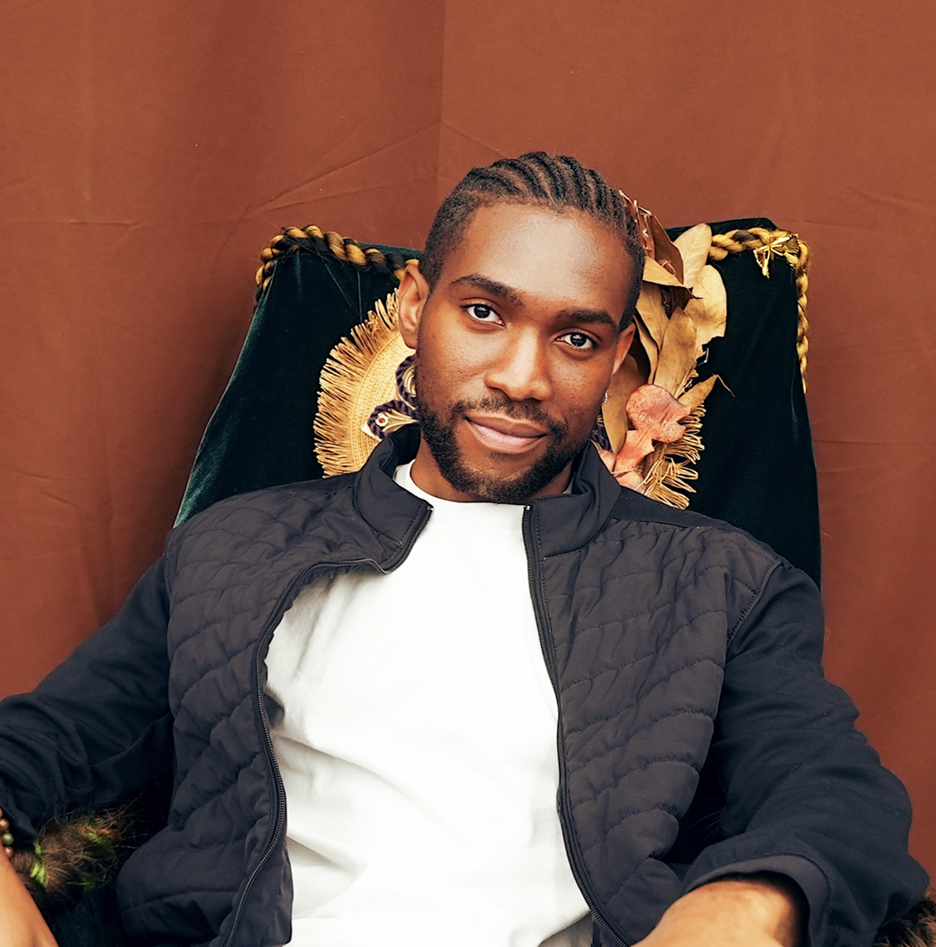 Sam Higgwe poses in front of a burnt orange background.