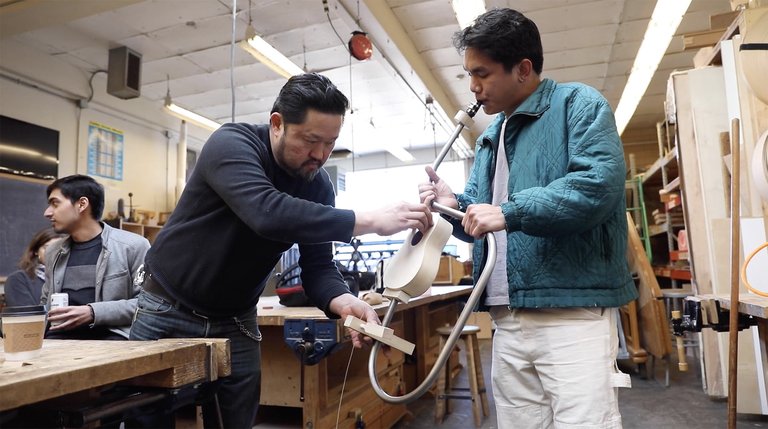 Adjunct professor Sung Kim steadies a sculptural instrument while a student tests its sonic properties.
