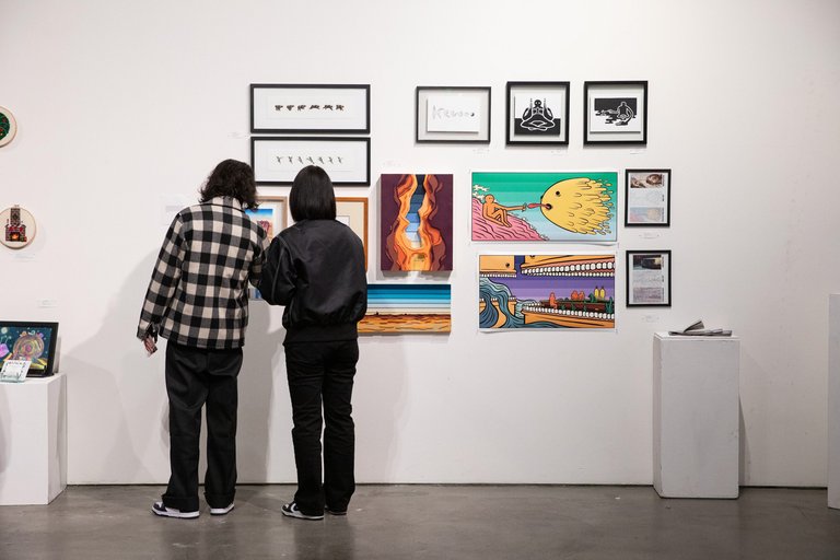 Visitors take in illustrations and graphics arranged neatly on a gallery wall.