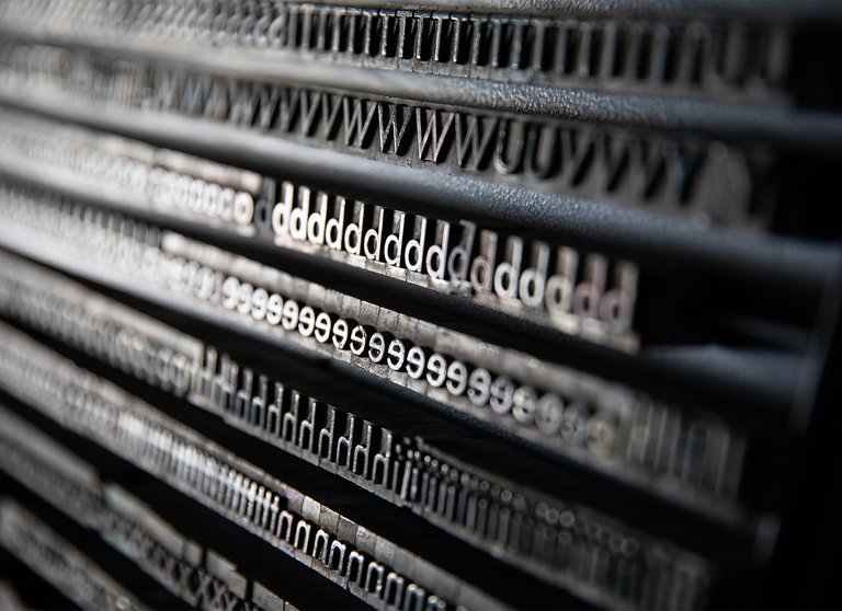 A close-up of a letterpress with the letters T, W, d, e, and h repeating.