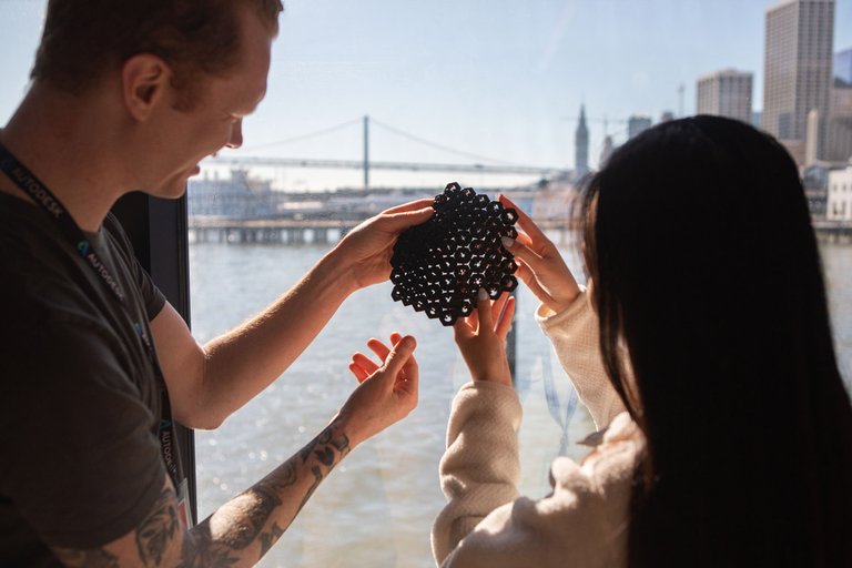 Interior Design students examine their 3D-printed work in the window light.