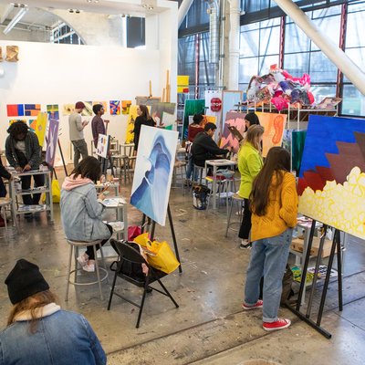 A studio full of students working on canvas paintings
