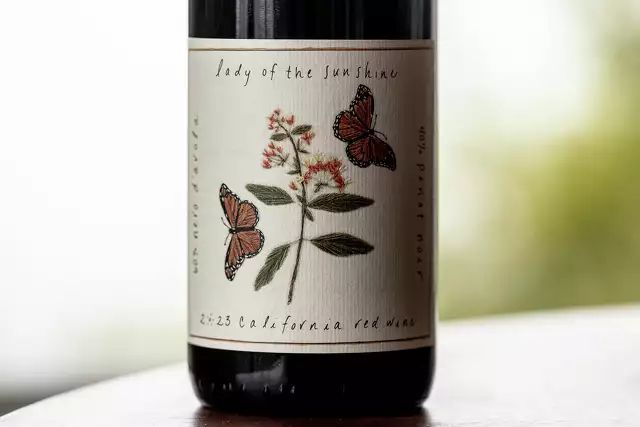 A highly textured paper and embossed flowers and butterflies on a wine bottle.