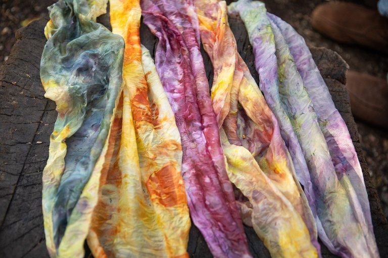 Multi-colored hand-dyed fabric pieces drying outside on a tree stump