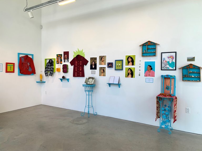 An exhibition opening with photos and blue furniture plus other objects.