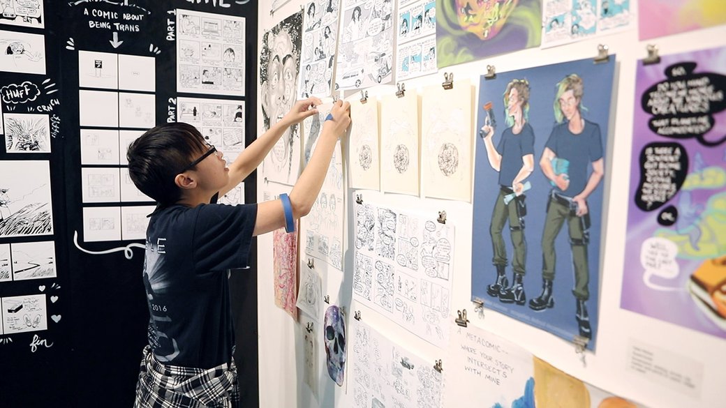 A student pins up a comic in an exhibition.