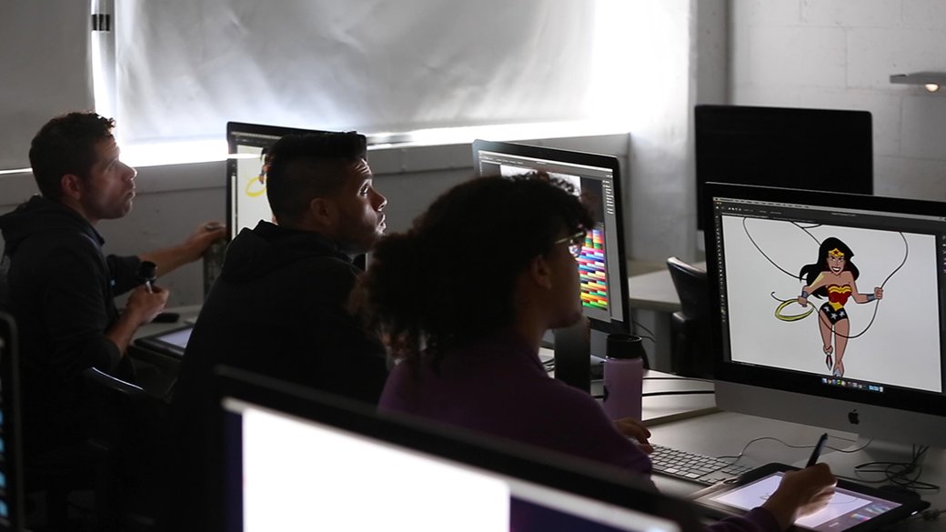 Three students work on comics in the computer lab.