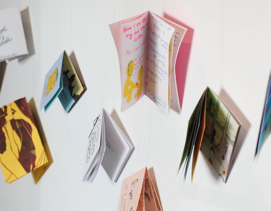 An installation of colorful comics suspended in a white space.