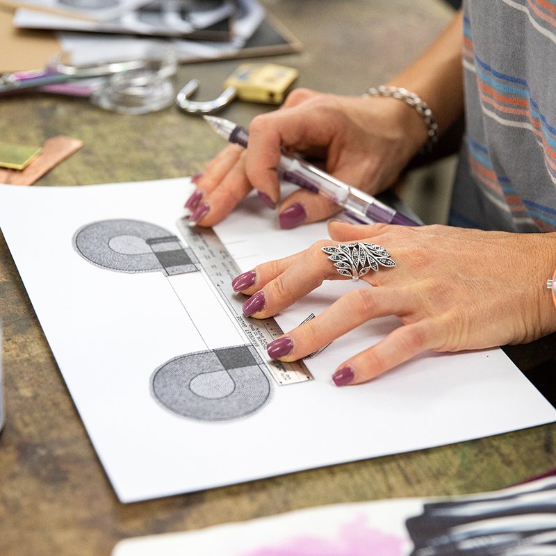 A person's hands measuring a shape on a piece of paper.