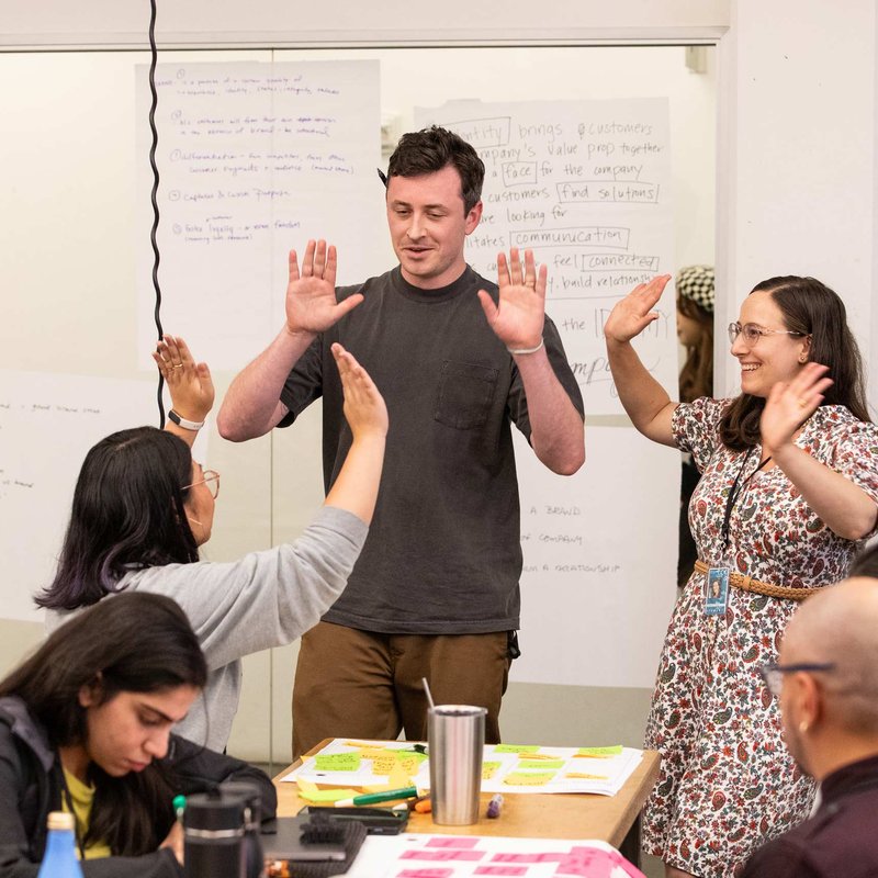 DMBA students celebrating their teamwork by doing a high-five circle.
