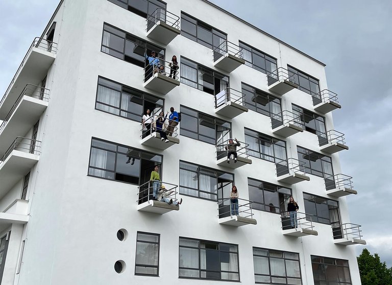 Students stand on the jutting balconies of a modernist building.