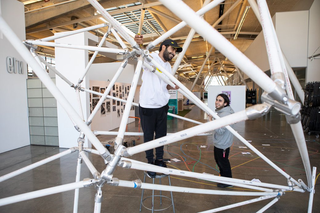Two students working on a PVC pipe structure.