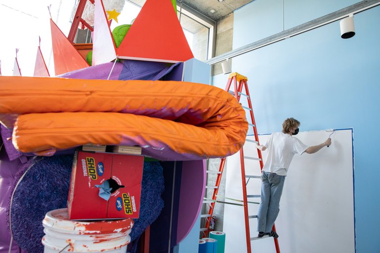Graduate student installing artwork inside of a gallery