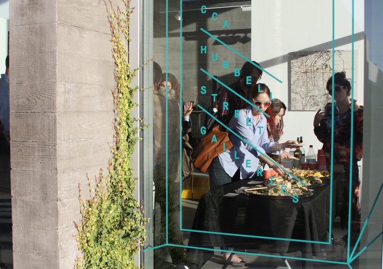 view of opening art reception through window at Hubbell St Galleries