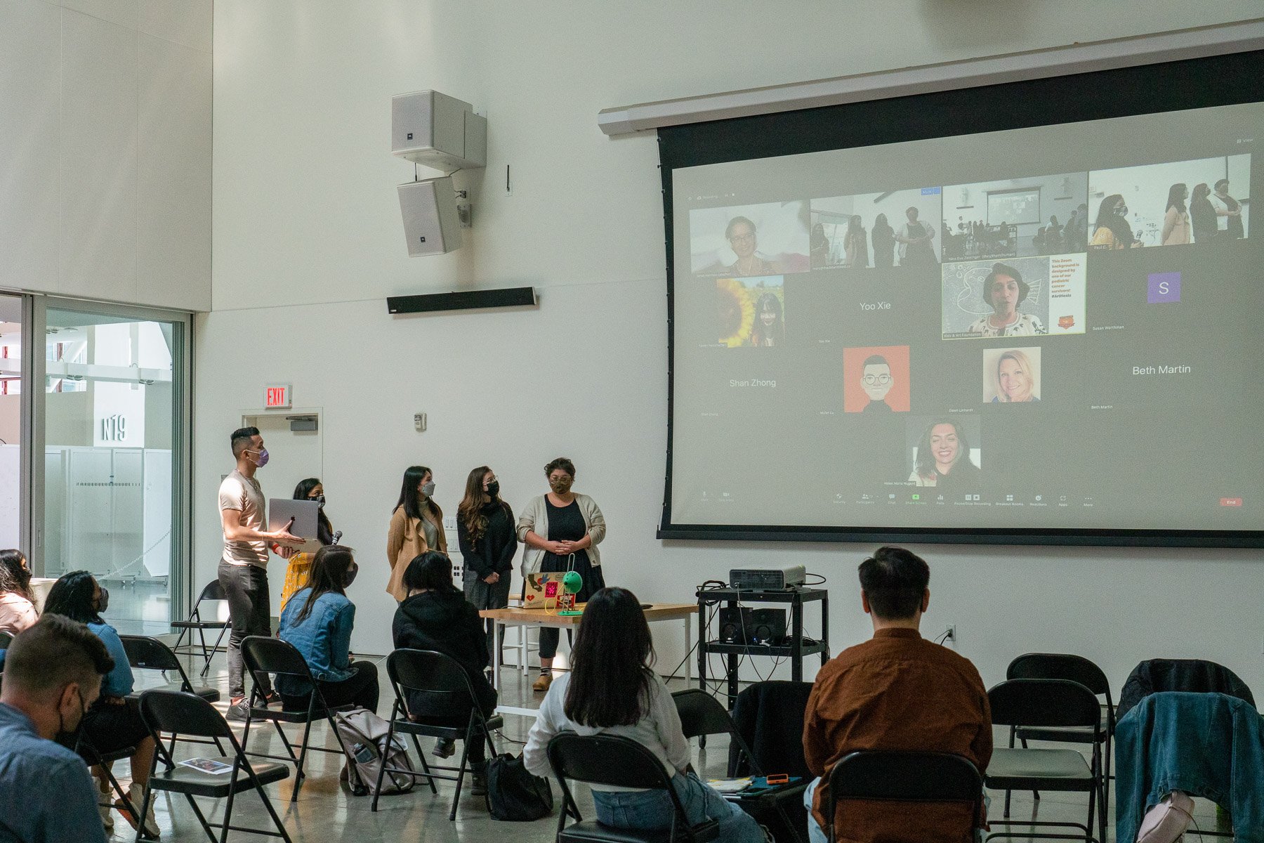 A photo of a group of students giving a presentation in person and over Zoom.