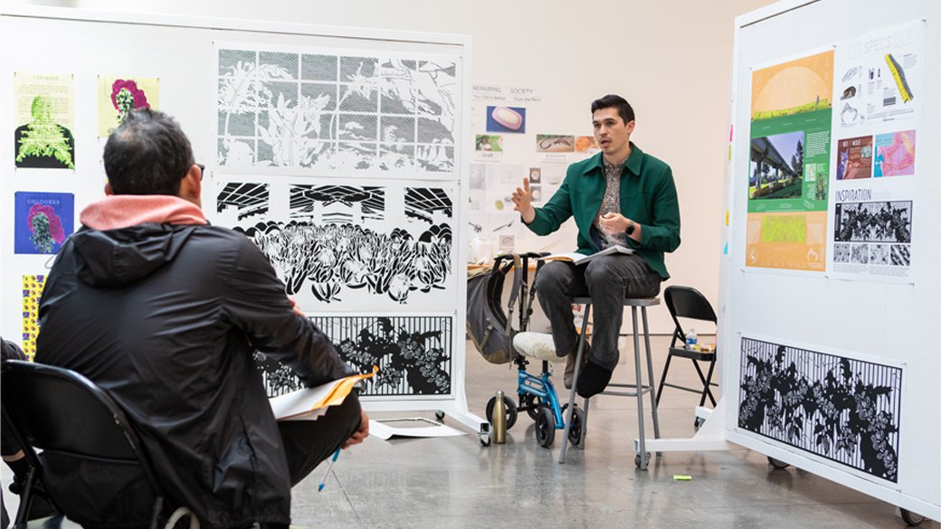 A design workshop in progress, led by a man wearing a green jacket.