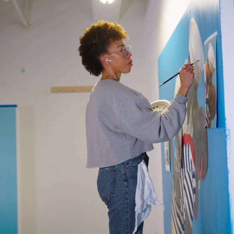 An artist painting on a large canvas.