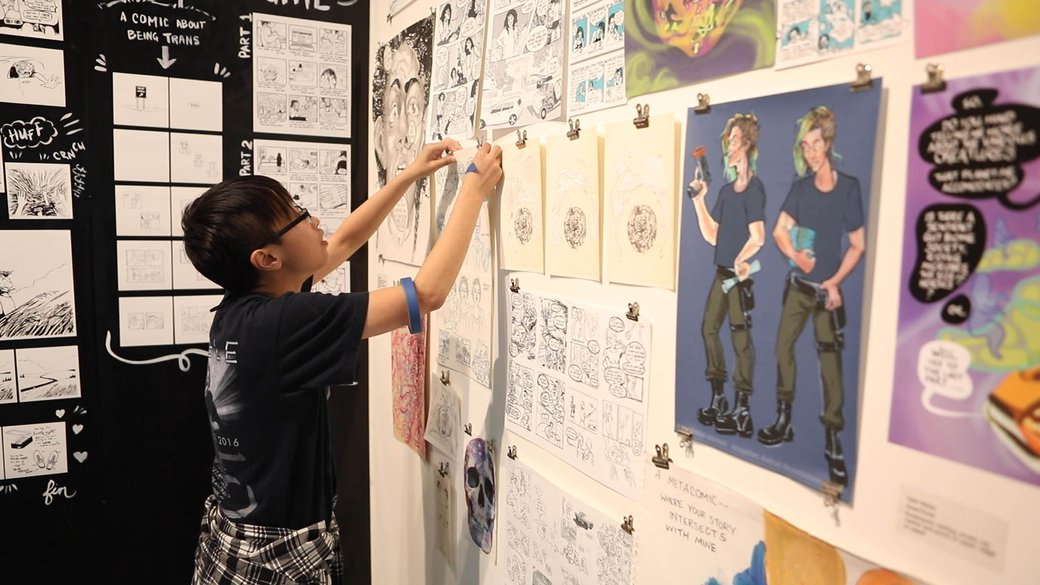 A student hangs artwork in CCA's annual Emanata Comics Gallery Exhibition