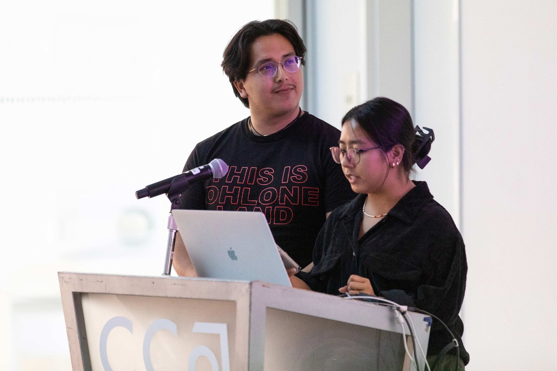 Two students stand at a podium together.
