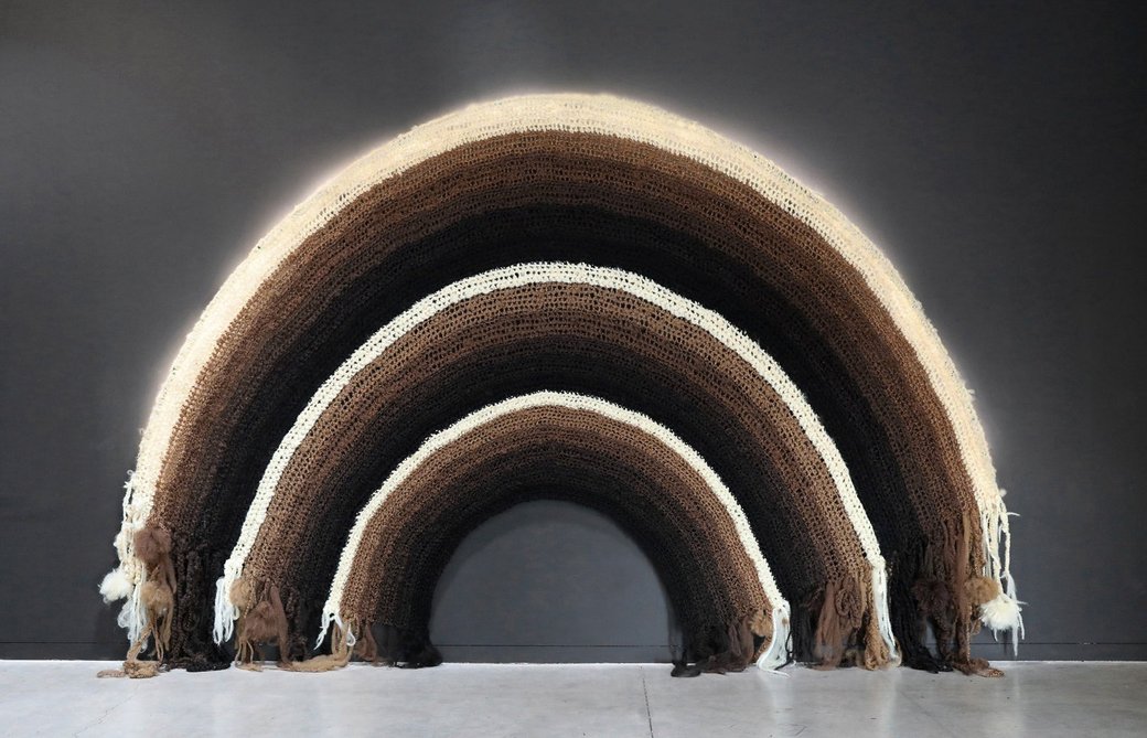 Photo of an artwork of a woven rainbow with bands of different rich hues of brown, blacks, and beige.
