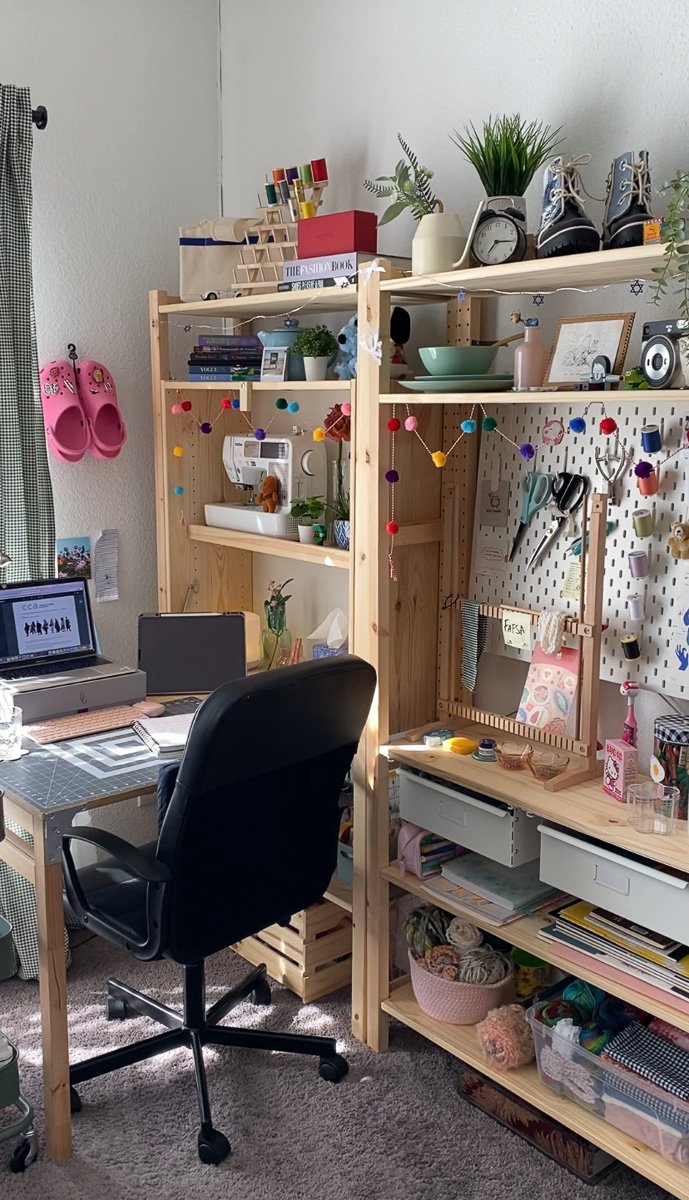A small desk, a rolling chair, and a wooden shelving unit to the right showcases Rodriguez’s designs, process, and materials.