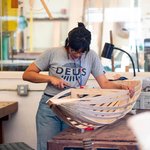 Photo of Balqis Indriyani working over the wood frame of a boat-shaped object.