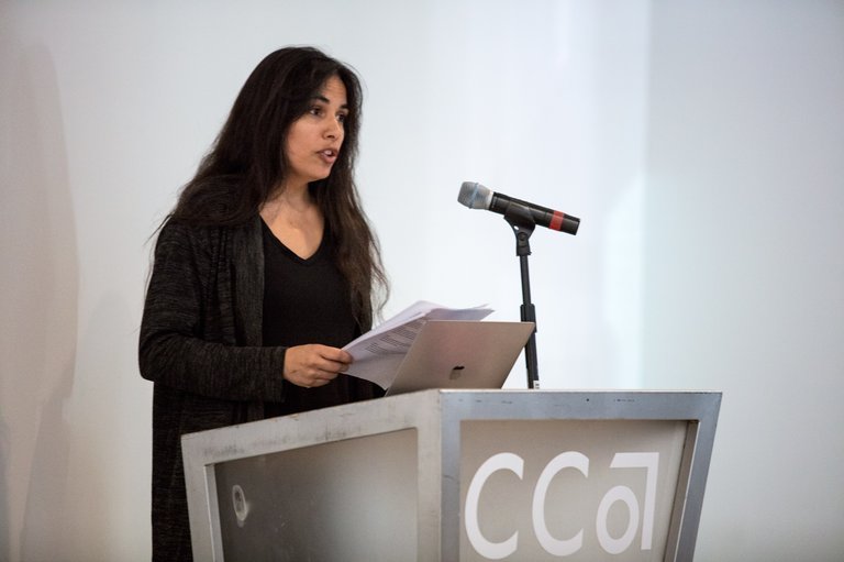 A student reads her thesis at a podium.