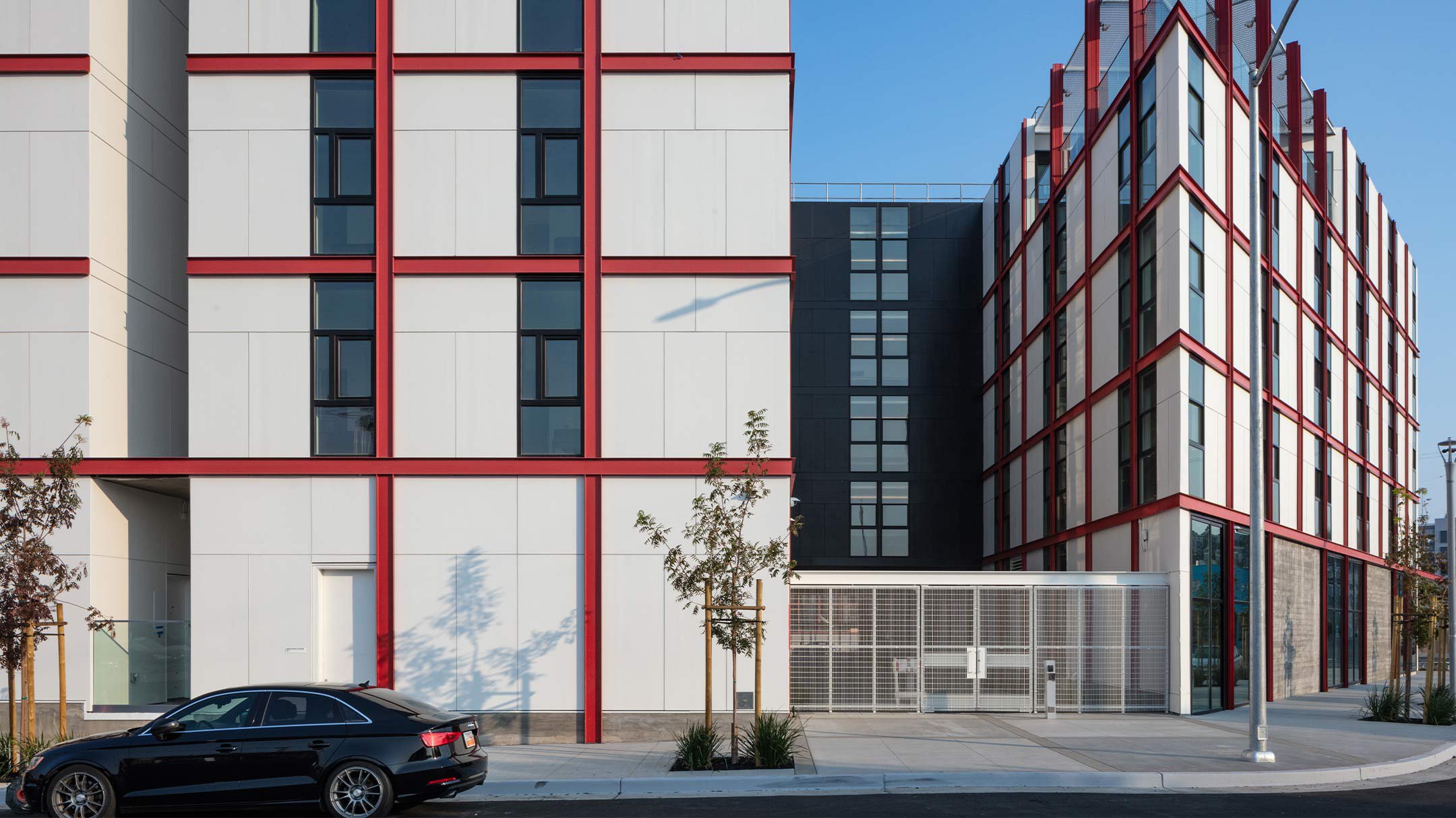 Founders Hall, a modern, five-story white student residence hall with red accents and a distinctive triangular roof deck that can be seen against a bright blue sky.