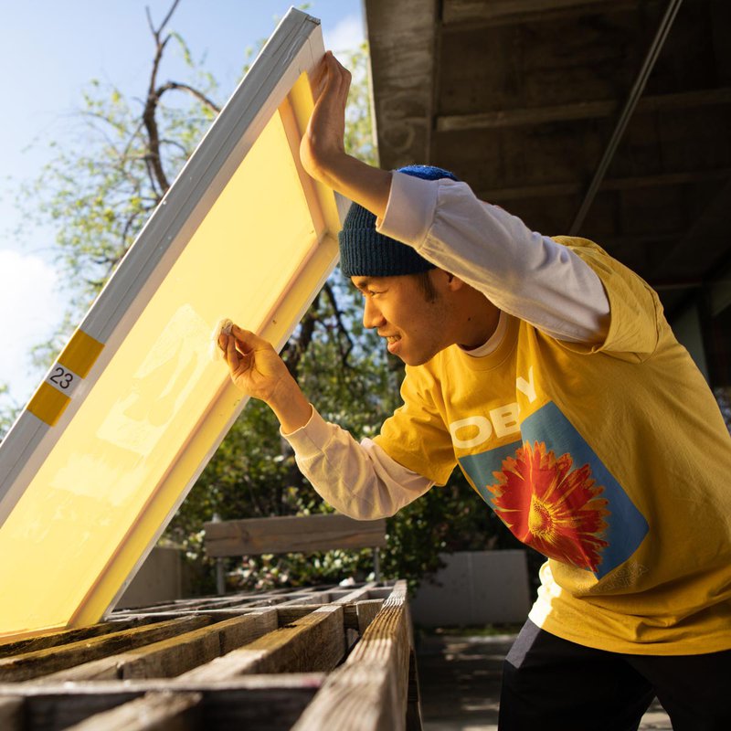 An artist cleans a silk screen outside of the print studio.