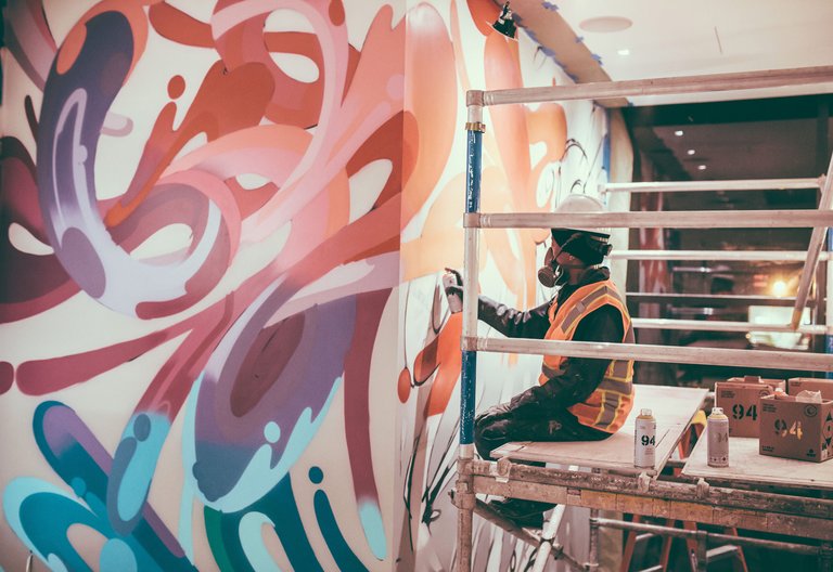 Painter working on large spray painted mural