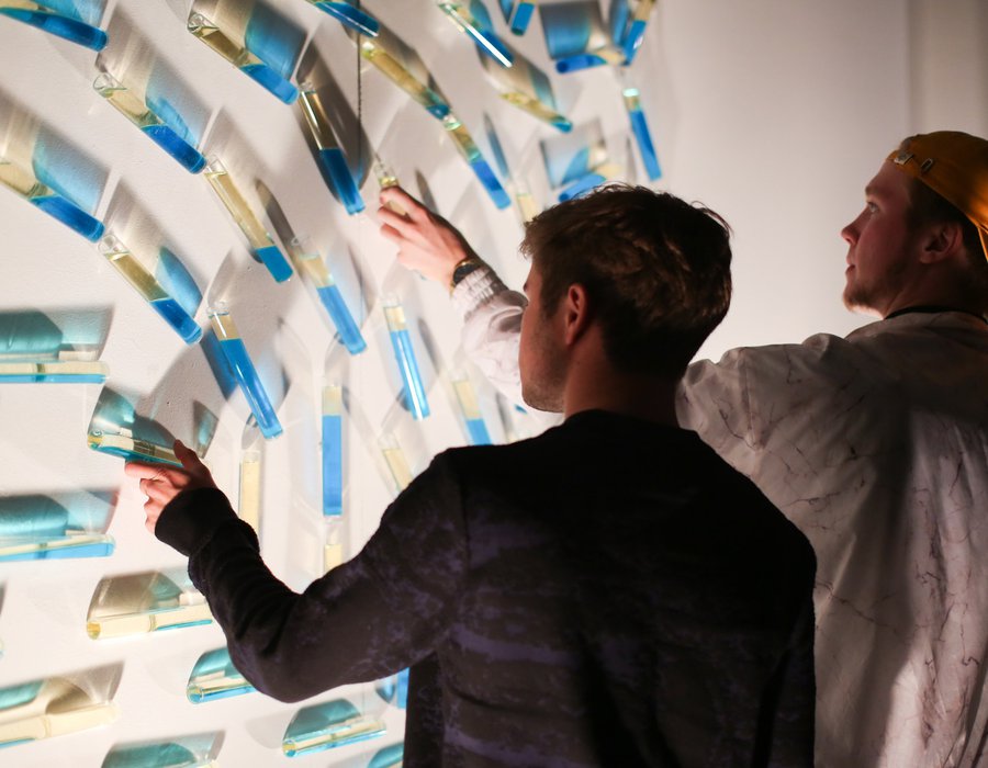 Two people engaging with fluid-filled vessels at an exhibition at Hubbell Street Galleries.