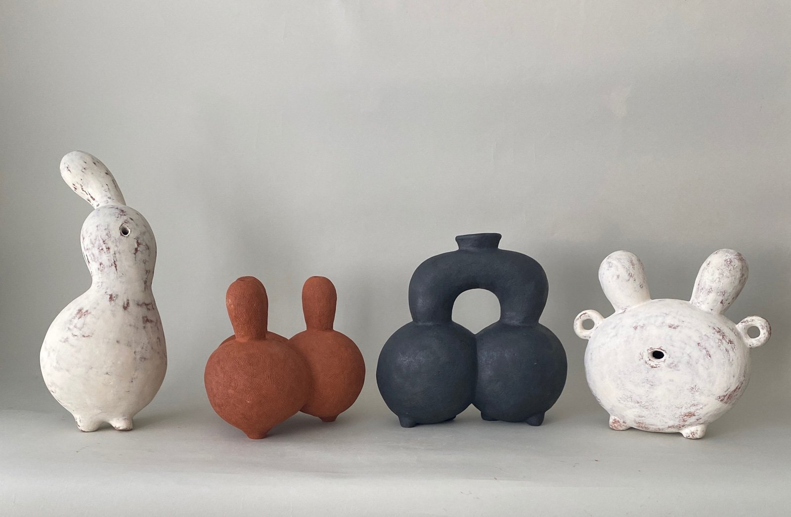 A photo of four abstract ceramic sculptural works in different shapes and colors.