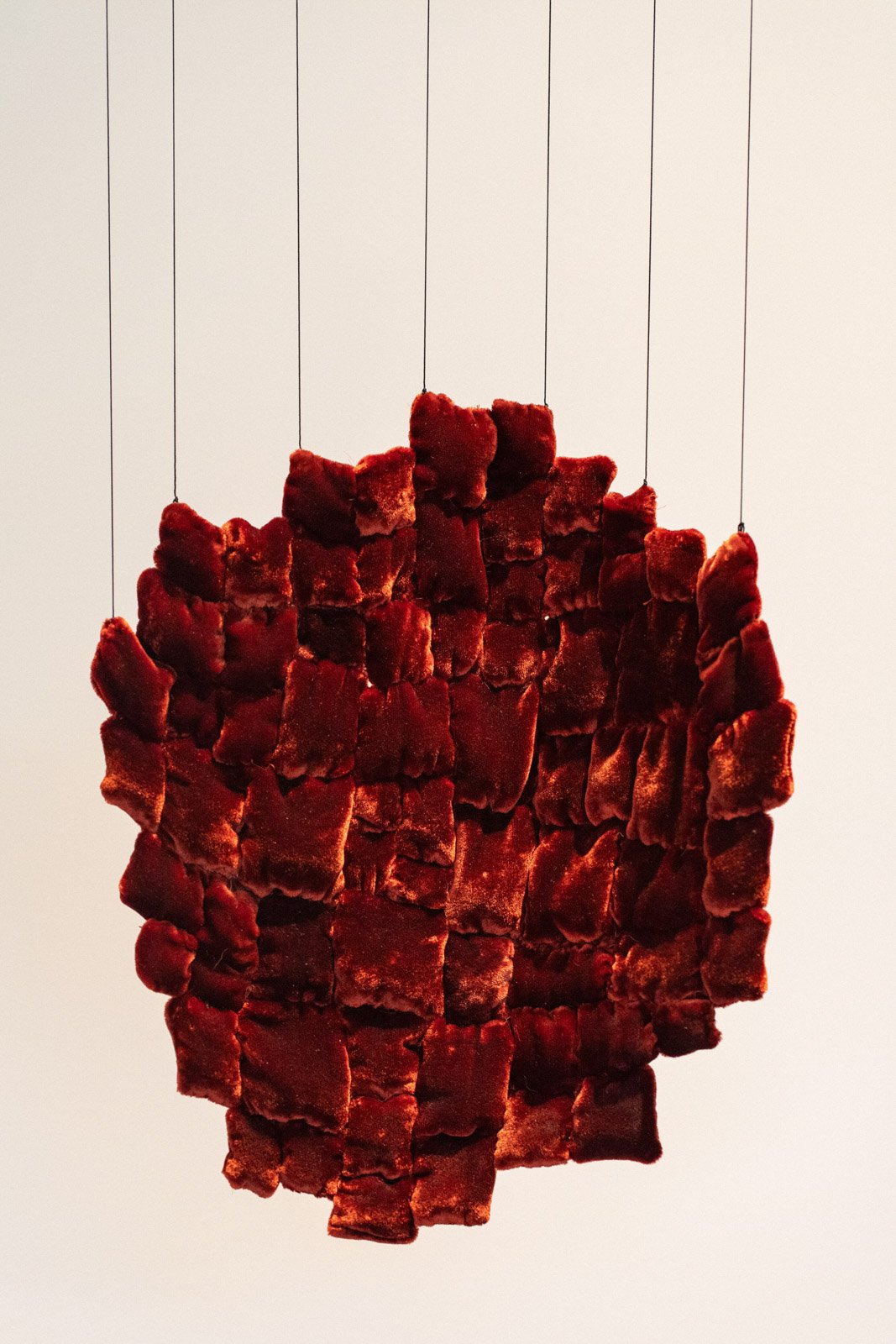 Installation view of rich velvety tones fabric stitched together in an abstract oval shape.