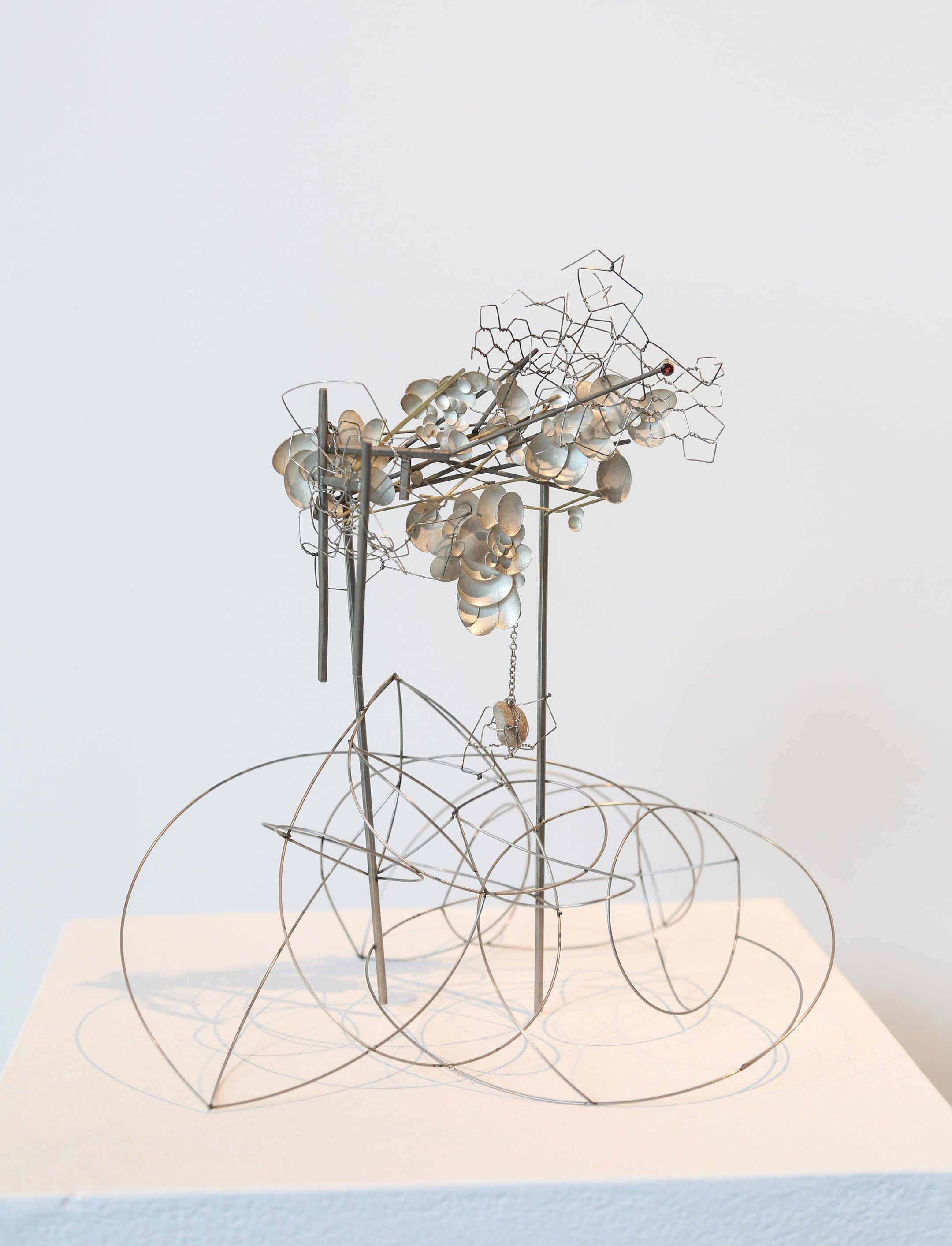 A photo of a metallic sculptural artwork comprised of individual oval-shaped silver pieces.