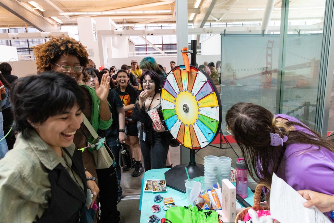 A group of people gathered around a table, engaging with a colorful spinning wheel in the center.