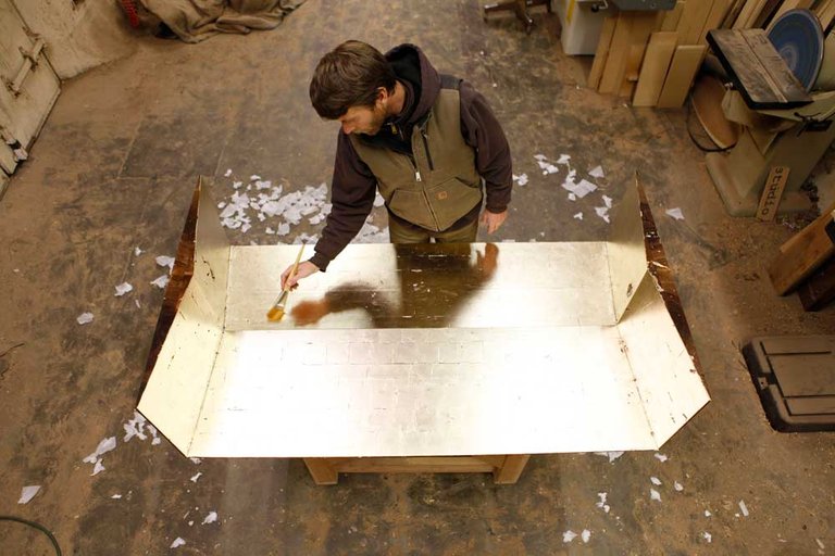 Bay Area furniture designer and CCA alumnus Florian Roeper puts the finishing touches on a gold-leafed surface in his Alameda atelier.