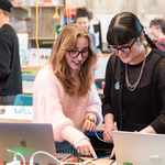 Two female students in a classroom playing with wearable technology