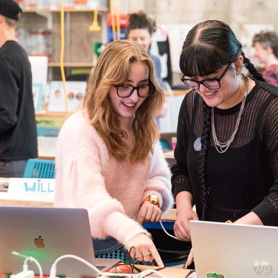 Two female students in a classroom playing with wearable technology