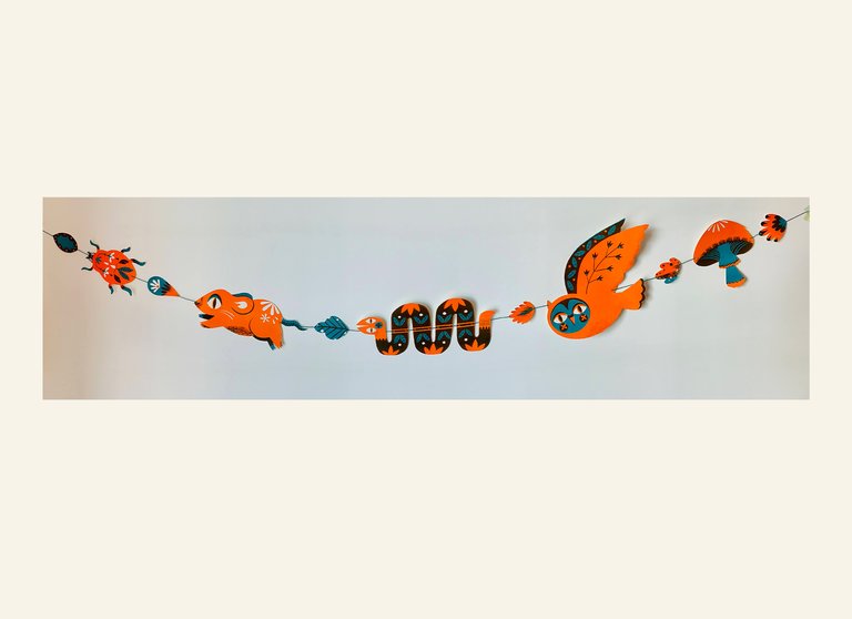 A decorative garland with a bug, a rodent, a snake, an owl, and a mushroom one after the other.
