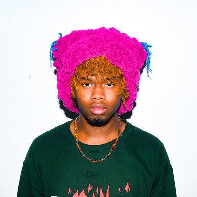 A headshot of Qadir Parris wearing a neon pink hat and black shirt