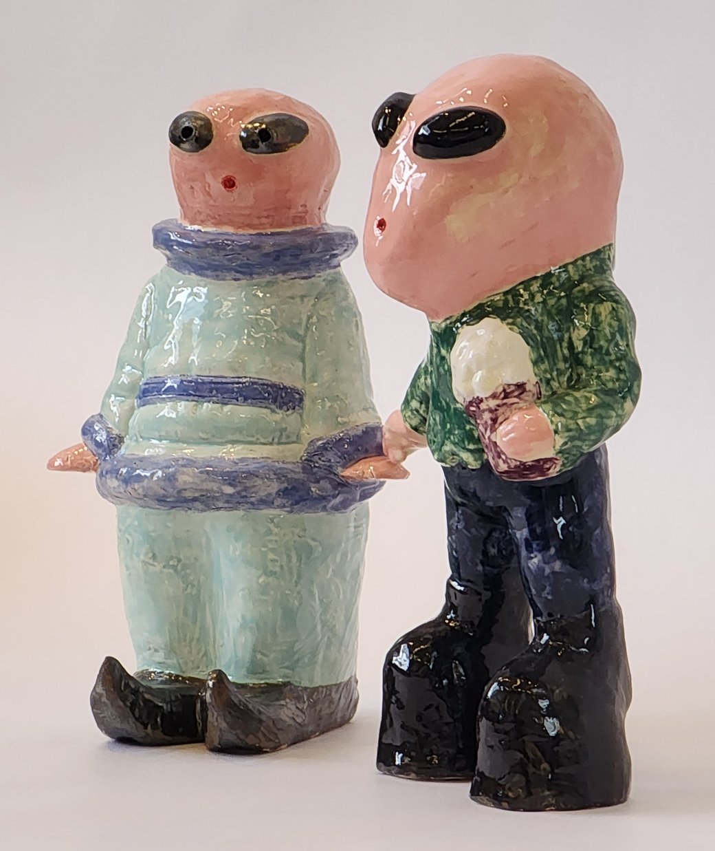 A photo of two ceramic figurines resembling extraterrestrials.