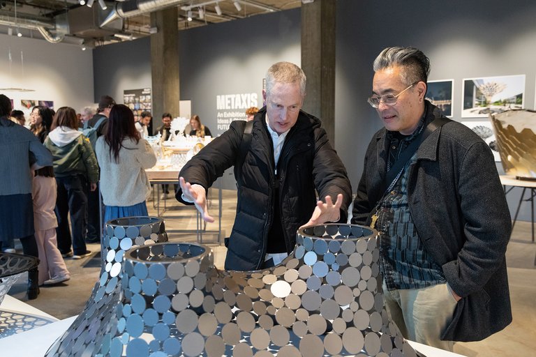 Two CCA faculty members look over artwork at the Metaxis reception.