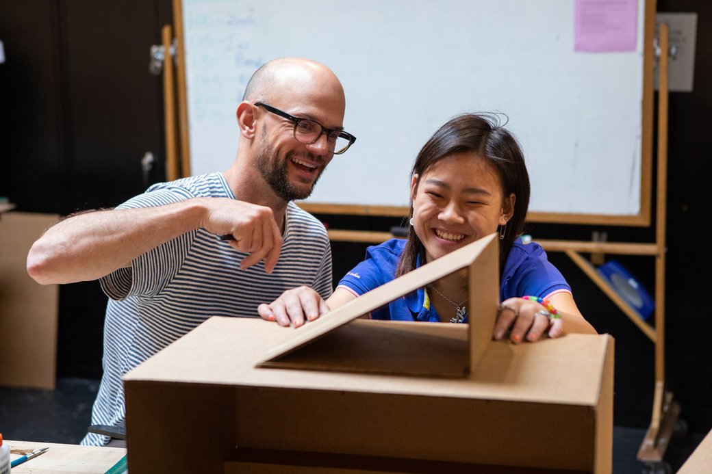Pre-college program student and faculty member assemble a box.