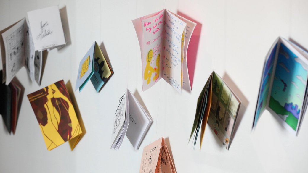 An installation of colorful comics suspended in a white space.