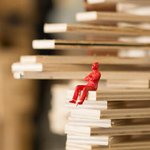 Red figure sitting on architectural model.
